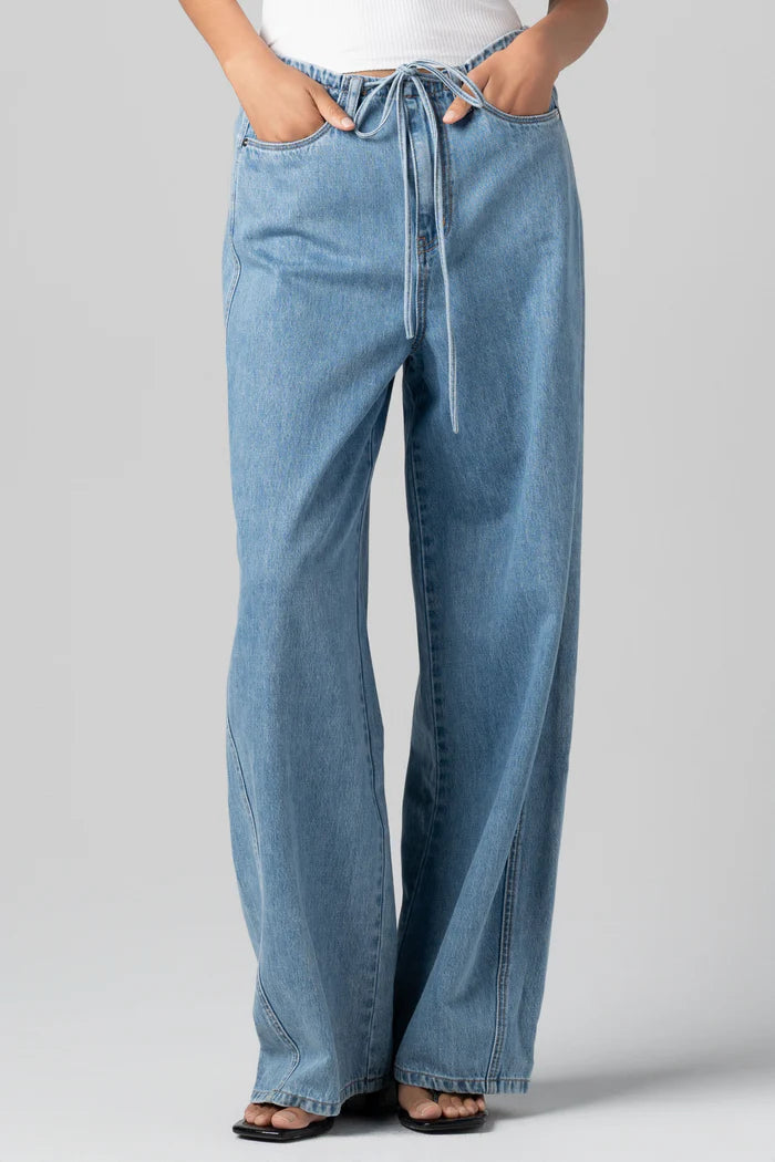 Woman wearing wide leg drawstring denim jeans with a relaxed fit and soft, flowy silhouette paired with a fitted tank