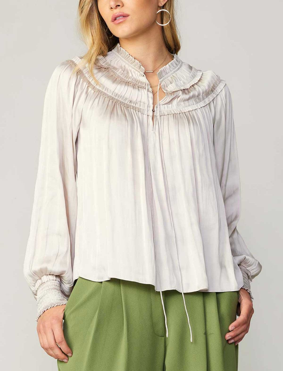 Current Air Ruffle Smock Detail Blouse White. This split-neck blouse exudes an aura of romance in a flowy silhouette with long sleeves and smocked cuffs. Accented by a dainty tied neckline and delicate ruffles at the shoulders, it's a breezy expression of feminine charm.