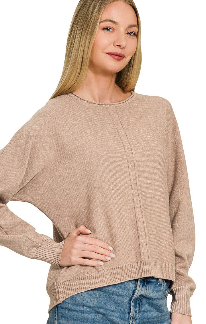 Model wearing a relaxed-fit lightweight knit sweater with drop shoulders, exposed center seam detailing, ribbed cuffs, and a ribbed hem paired with blue denim.