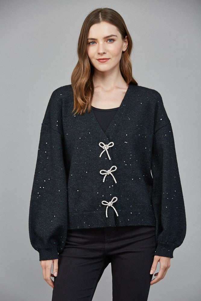 bow detail sweater, embellished knit top, women’s statement sweater, feminine knitwear, chic boutique sweater, V-neck sweater women, dressy casual sweater, holiday knit top, fashion-forward sweater, trendy women’s knit
