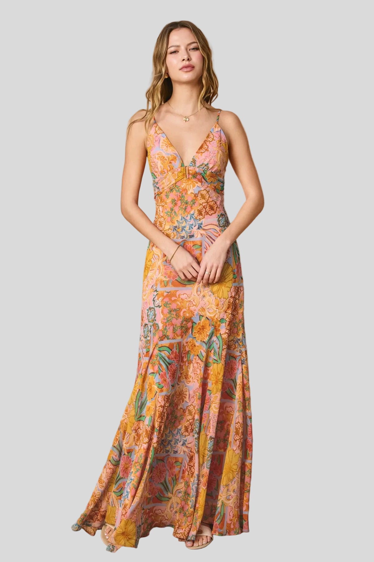 Printed maxi dress with floral patchwork pattern, spaghetti straps, deep V-neckline, and flowing full-length skirt.