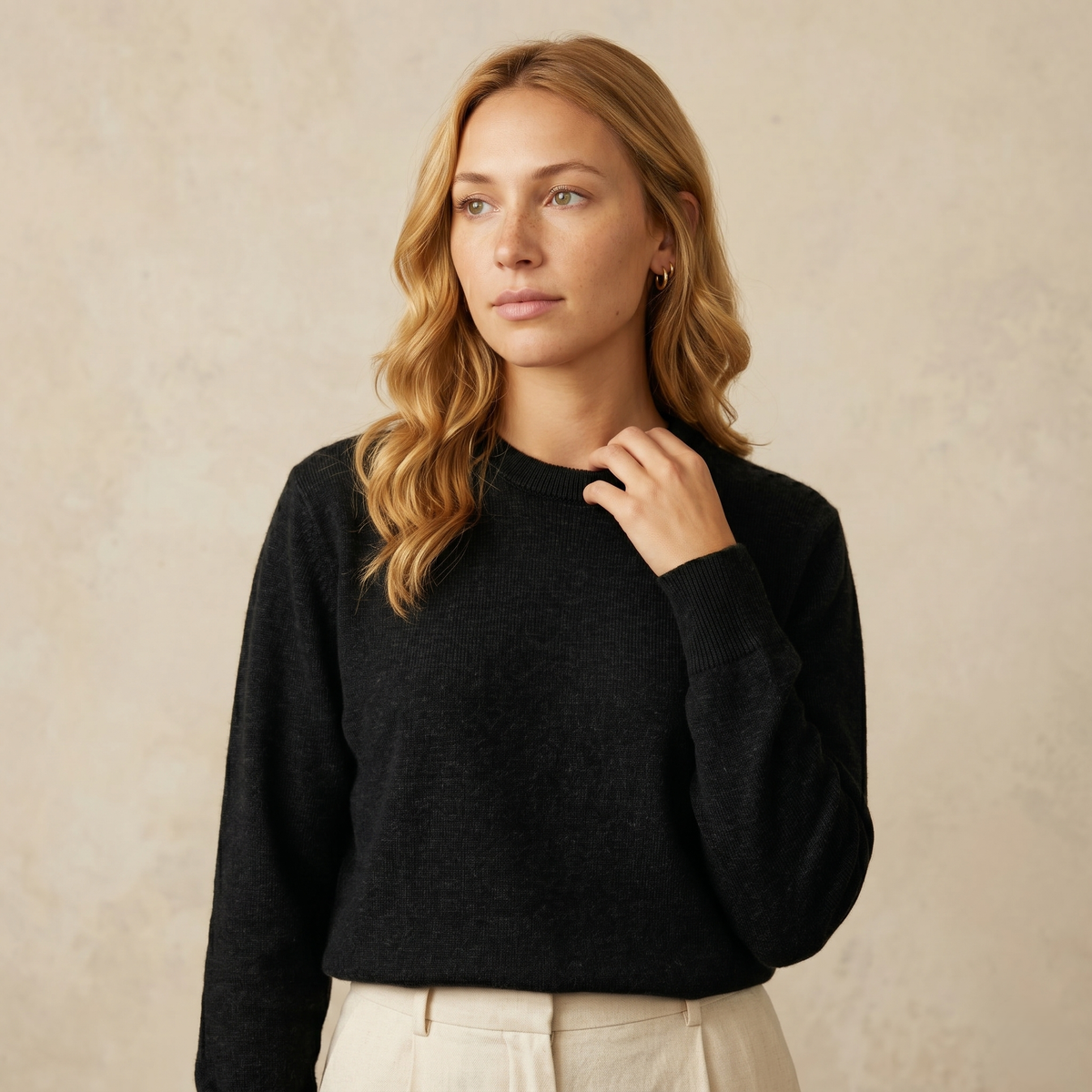 Woman wearing a black sweater against a beige background