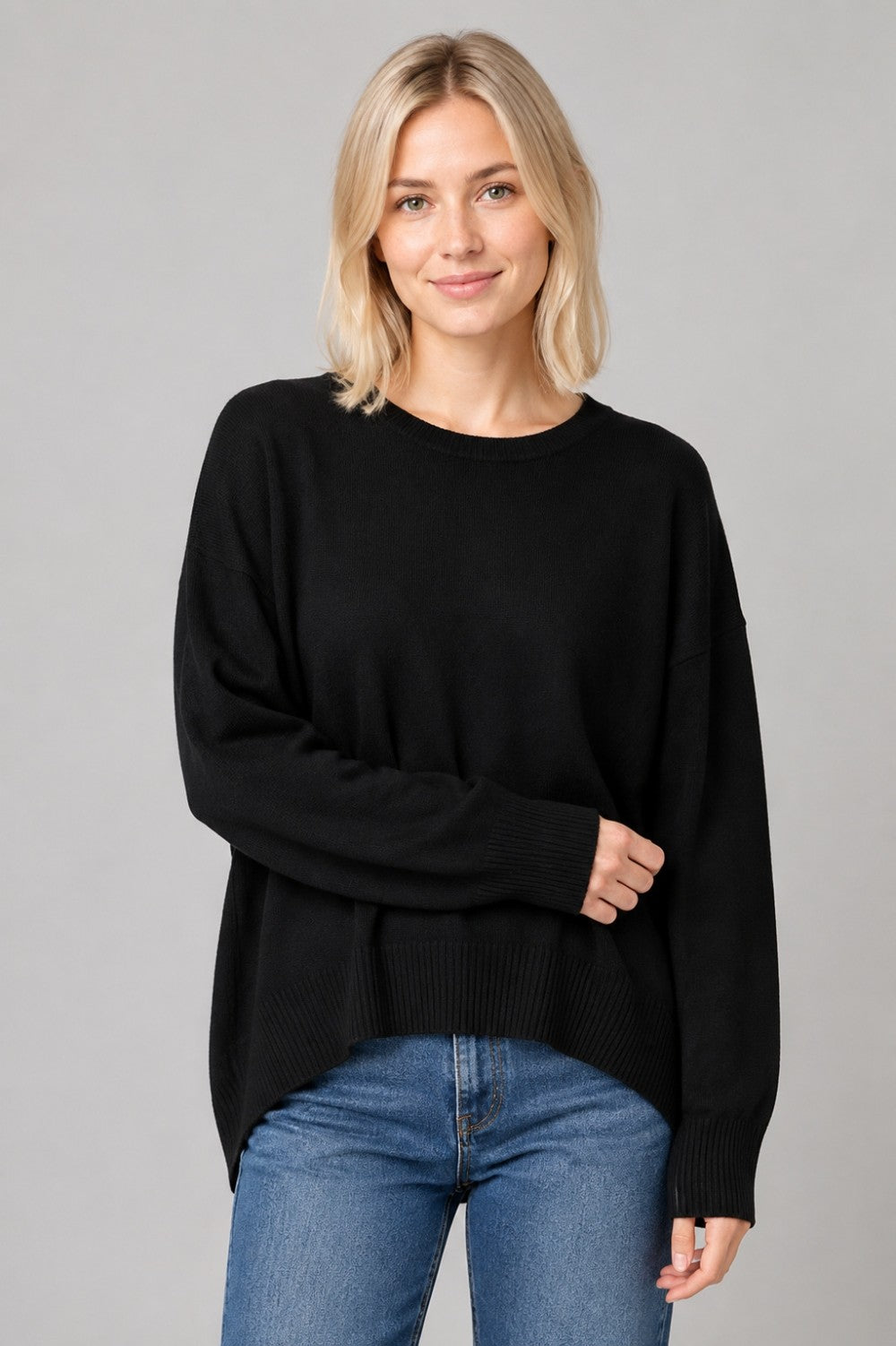 Woman wearing a relaxed crewneck sweater with dropped shoulders, ribbed trim, side slits, and a high-low hem.