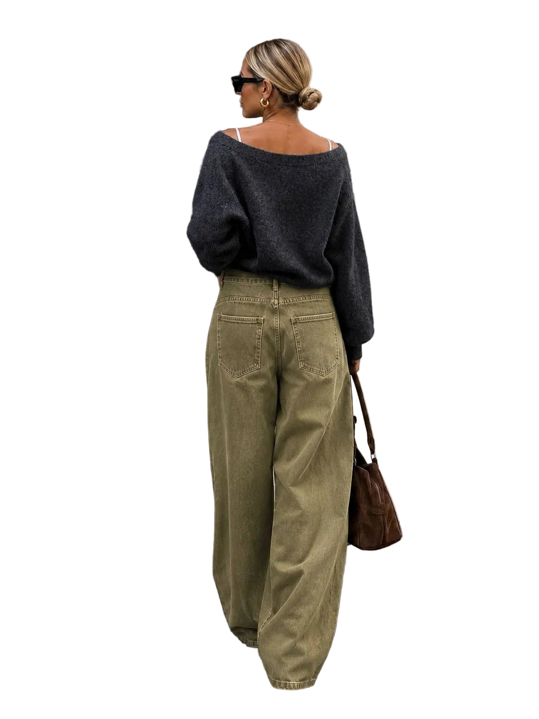 A woman photographed from behind wearing a dark charcoal off-the-shoulder knit sweater and wide-leg olive green pants, standing on a city sidewalk next to a black door and stone wall.