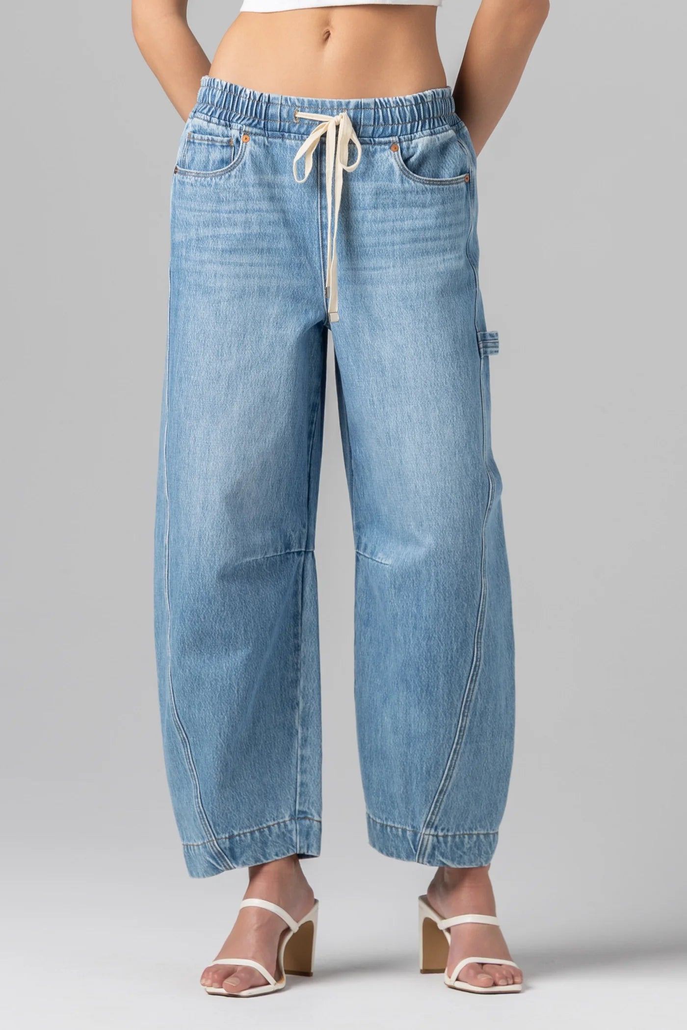 Woman wearing relaxed drawstring barrel leg denim jeans with a loose fit and casual silhouette paired with heels