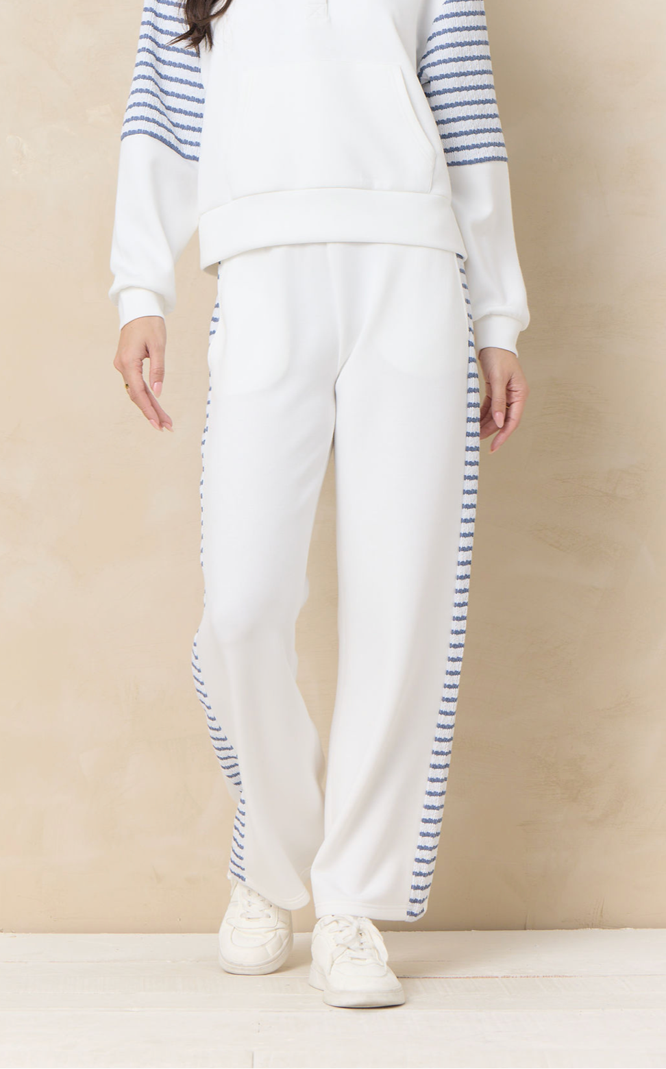 Ivory wide leg lounge pants with striped side panel detailing paired with coordinating relaxed sweatshirt and sneakers.