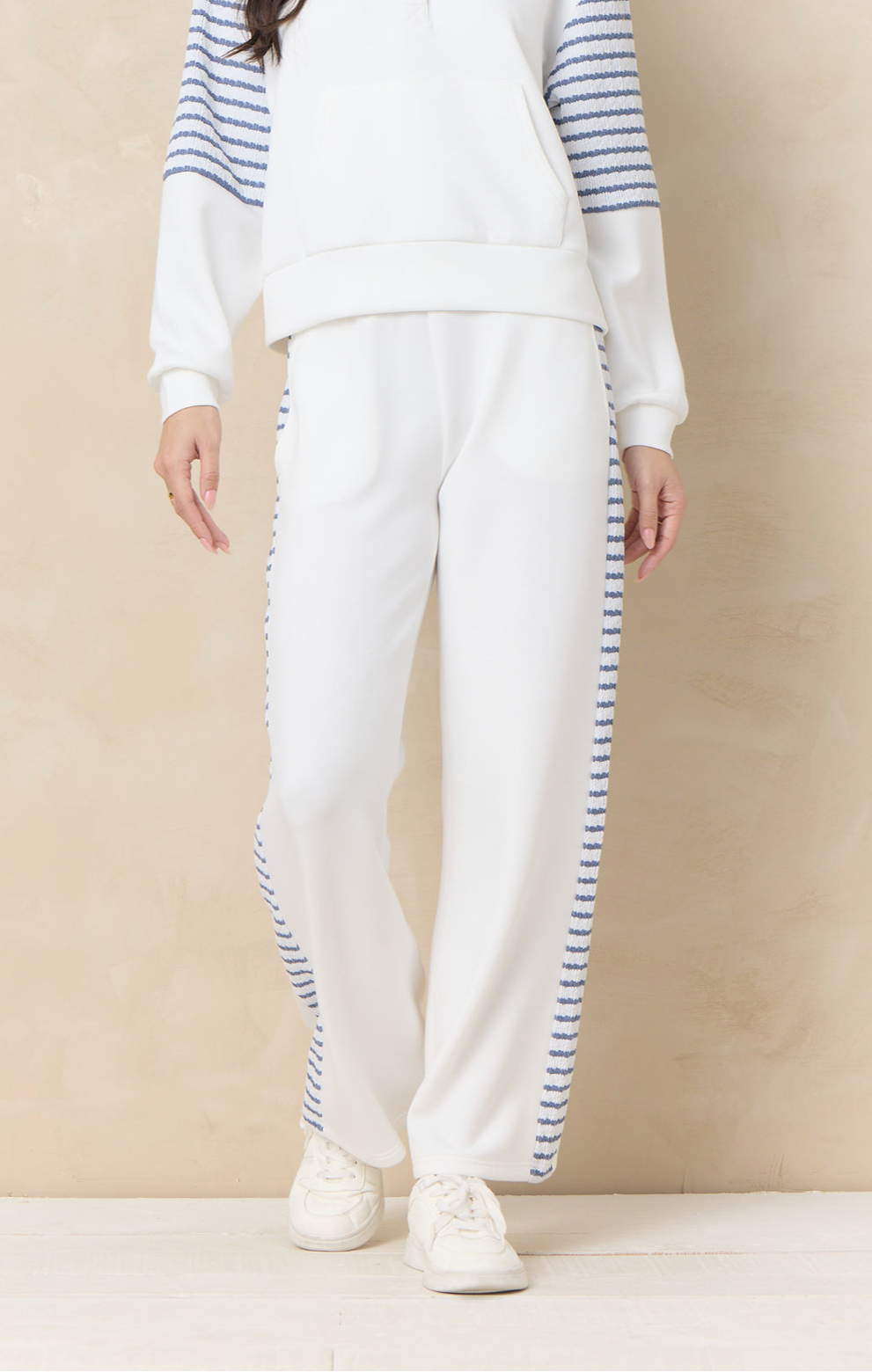 Ivory wide leg lounge pants with striped side panel detailing paired with coordinating relaxed sweatshirt and sneakers.