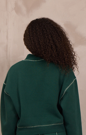 Woman wearing a mockneck pullover with contrast stitching.
