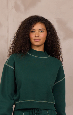 Woman wearing a mockneck pullover with contrast stitching.
