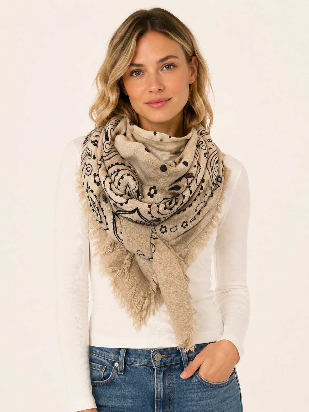 Woman wearing an oversized square scarf with a bandana-inspired print and fringed edges.