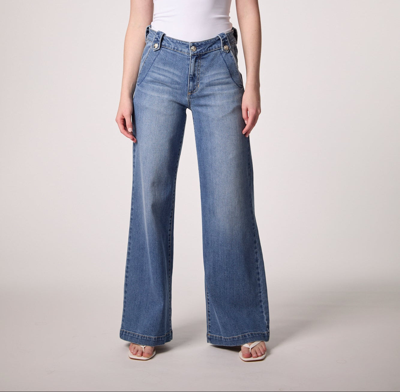 Woman wearing mid rise wide leg denim jeans with a relaxed fit and full length silhouette styled with a fitted tank