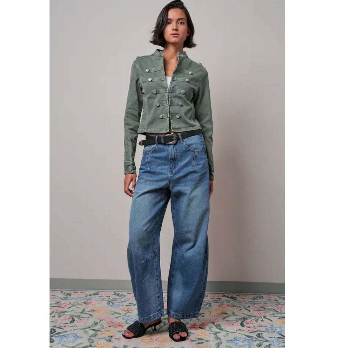 Military-inspired fitted denim jacket with a stand collar, decorative button tabs, and elbow patches