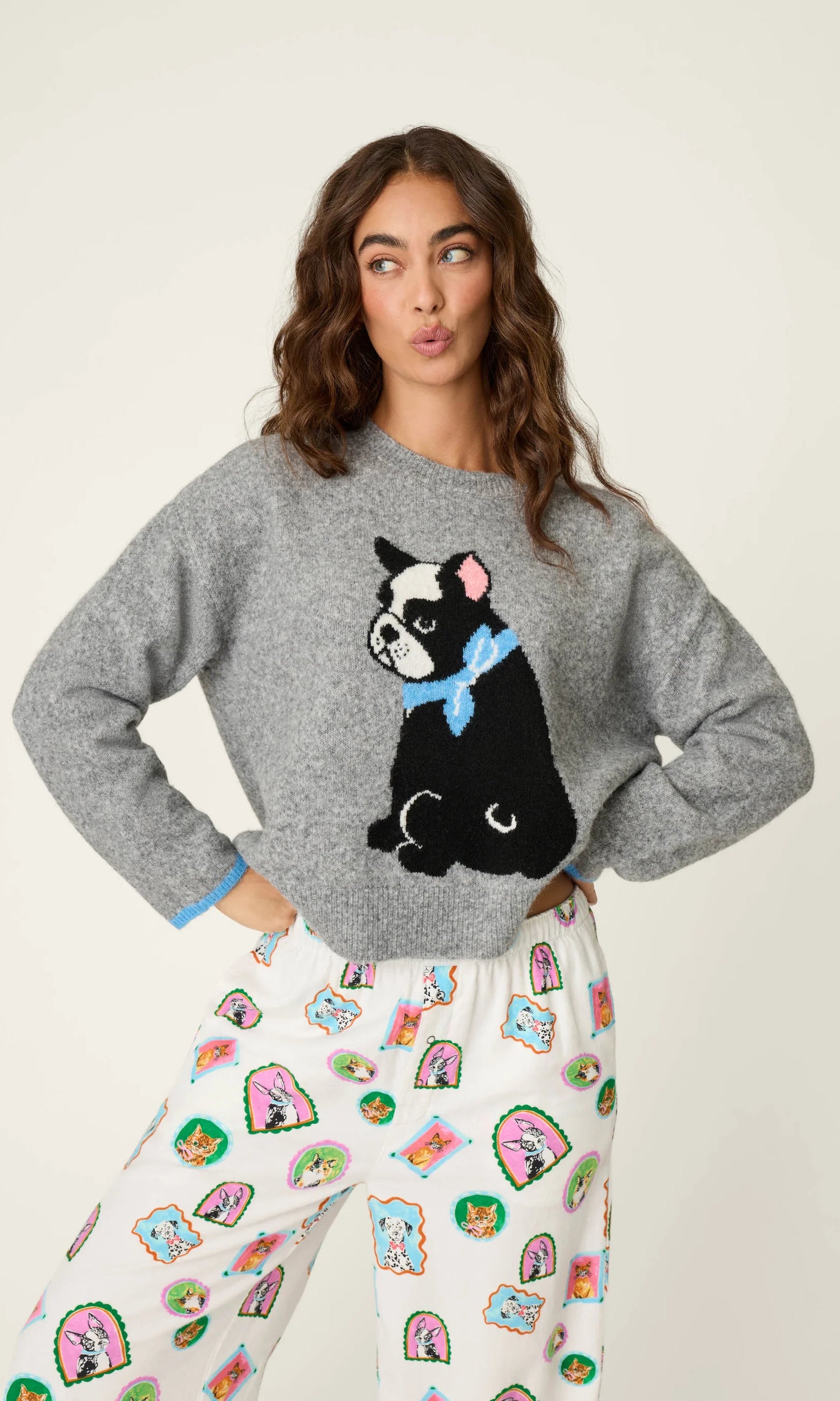 Woman wearing a crewneck sweater with a large French bulldog graphic and contrast cuff trim.