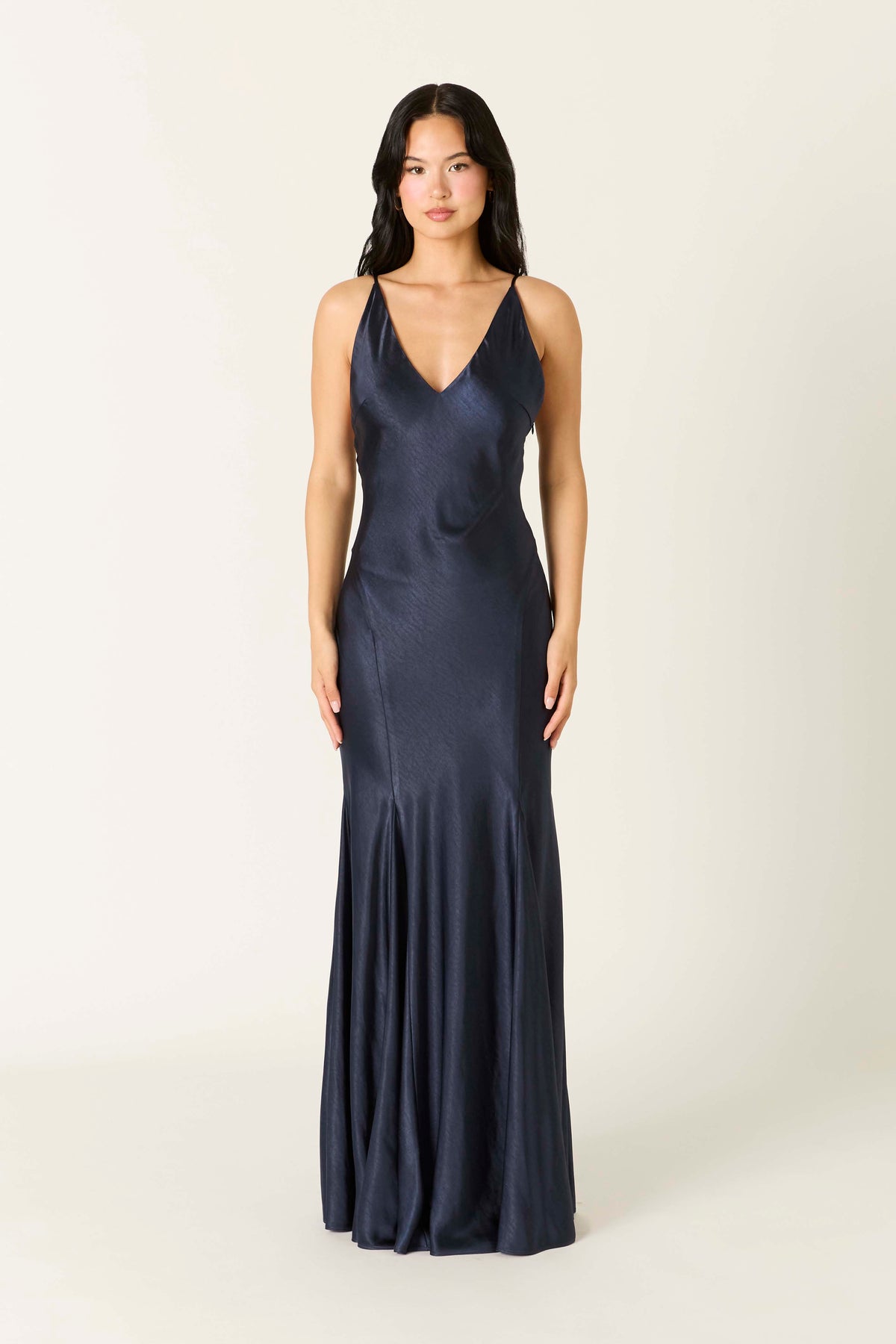 Model wearing a satin maxi slip dress with a V-neckline, thin adjustable straps, low V-back, and flowing flared hem.