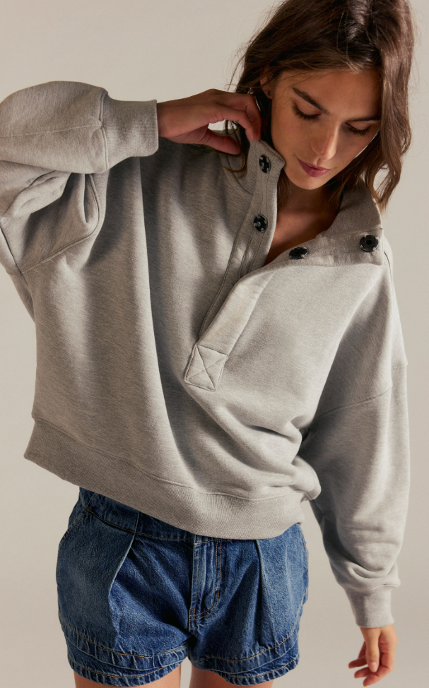 Model wearing an oversized fleece snap-neck pullover sweatshirt with a relaxed fit and long sleeves paired with denim shorts.