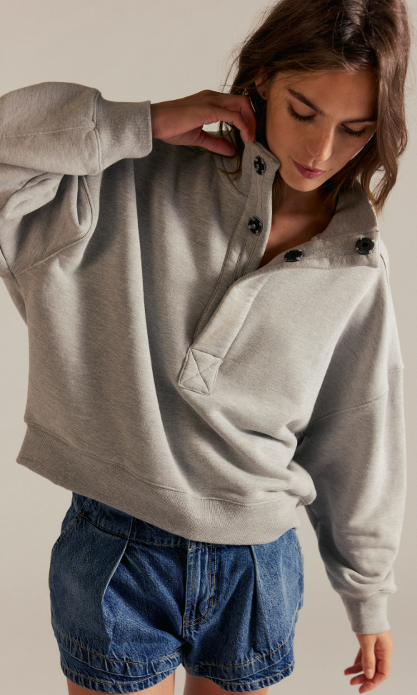 Model wearing an oversized fleece snap-neck pullover sweatshirt with a relaxed fit and long sleeves paired with denim shorts.