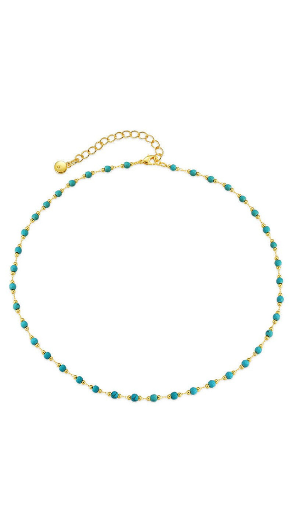 Delicate gold beaded necklace with turquoise-inspired stones and adjustable chain closure on a light background.