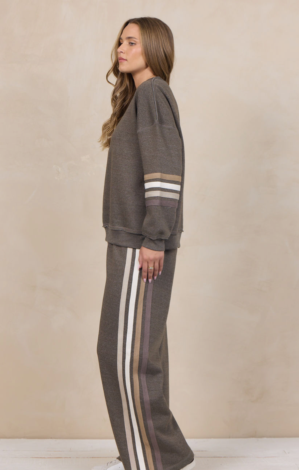 Woman wearing a heather fleece mockneck pullover with dropped shoulders and striped cuffs.