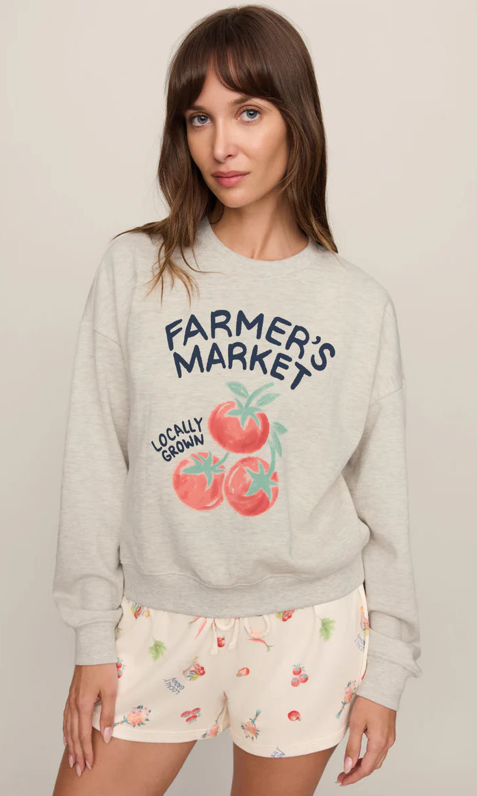 Model wearing a relaxed-fit graphic sweatshirt featuring a vintage-inspired farmer's market tomato graphic paired with printed lounge shorts.