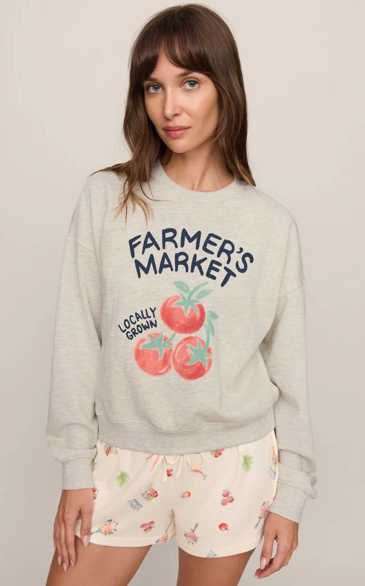 Model wearing a relaxed-fit graphic sweatshirt featuring a vintage-inspired farmer's market tomato graphic paired with printed lounge shorts.