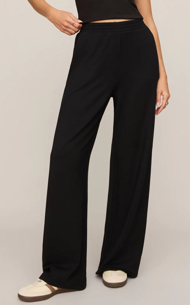 Model wearing ultra-soft black wide-leg lounge pants with a pull-on waistband and relaxed fit paired with sneakers.
