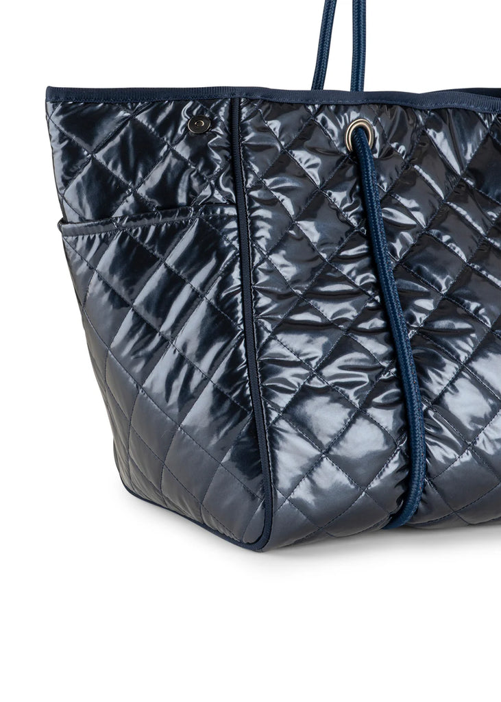 Haute Shore Greyson Navy Shiny Quilted Puffer. This shiny navy puffer tote is the perfect chic everyday bag to use as a carry all for your must haves, with a lightweight design that's perfect for when you're on the go.