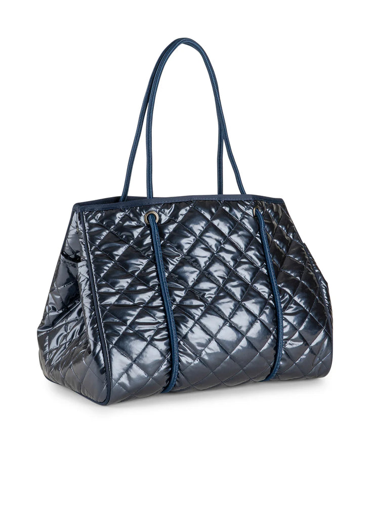 Haute Shore Greyson Navy Shiny Quilted Puffer. This shiny navy puffer tote is the perfect chic everyday bag to use as a carry all for your must haves, with a lightweight design that's perfect for when you're on the go.