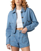 Woman wearing a cropped denim jacket with button front and front pockets styled with matching denim shorts