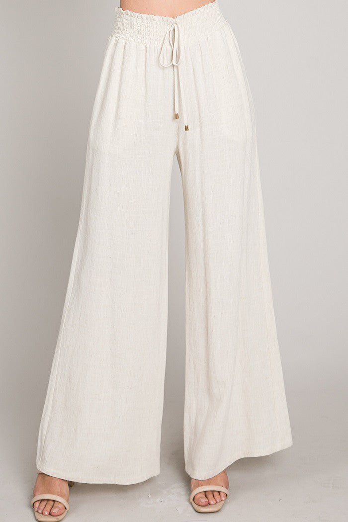 Model wearing wide-leg pants with a smocked drawstring waistband and relaxed fit.