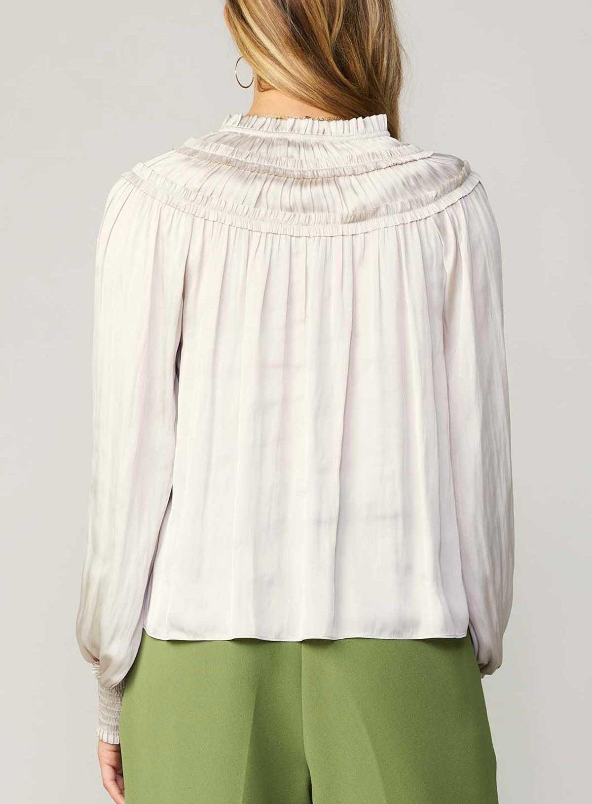 Current Air Ruffle Smock Detail Blouse White. This split-neck blouse exudes an aura of romance in a flowy silhouette with long sleeves and smocked cuffs. Accented by a dainty tied neckline and delicate ruffles at the shoulders, it's a breezy expression of feminine charm.