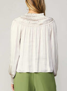 Current Air Ruffle Smock Detail Blouse White. This split-neck blouse exudes an aura of romance in a flowy silhouette with long sleeves and smocked cuffs. Accented by a dainty tied neckline and delicate ruffles at the shoulders, it's a breezy expression of feminine charm.