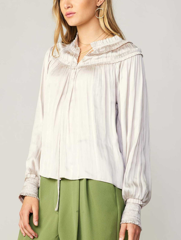 Current Air Ruffle Smock Detail Blouse White. This split-neck blouse exudes an aura of romance in a flowy silhouette with long sleeves and smocked cuffs. Accented by a dainty tied neckline and delicate ruffles at the shoulders, it's a breezy expression of feminine charm.