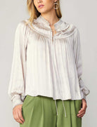 Current Air Ruffle Smock Detail Blouse White. This split-neck blouse exudes an aura of romance in a flowy silhouette with long sleeves and smocked cuffs. Accented by a dainty tied neckline and delicate ruffles at the shoulders, it's a breezy expression of feminine charm.
