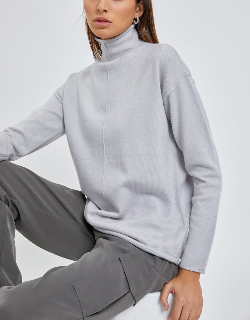 Moonbeam Line Detail Sweater Cloud. This cozy sweater features line details down the front and back and a mock neckline with a rolled hemline, a closet must have for fall and winter.