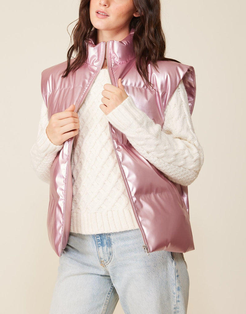 Zia Metallic Zip Up Puffer Vest Pearl Pink. Stand out this winter in this metallic pink zipper vest, the perfect layering piece that will keep you warm in the cutest way, featuring a zip front and side pockets.