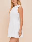 Tamara High Neck Mini Dress White. This adorable mini dress features a high neck and a-line fit with a zip close back, so easy to dress up with heels or down with sneakers and a denim jacket.
