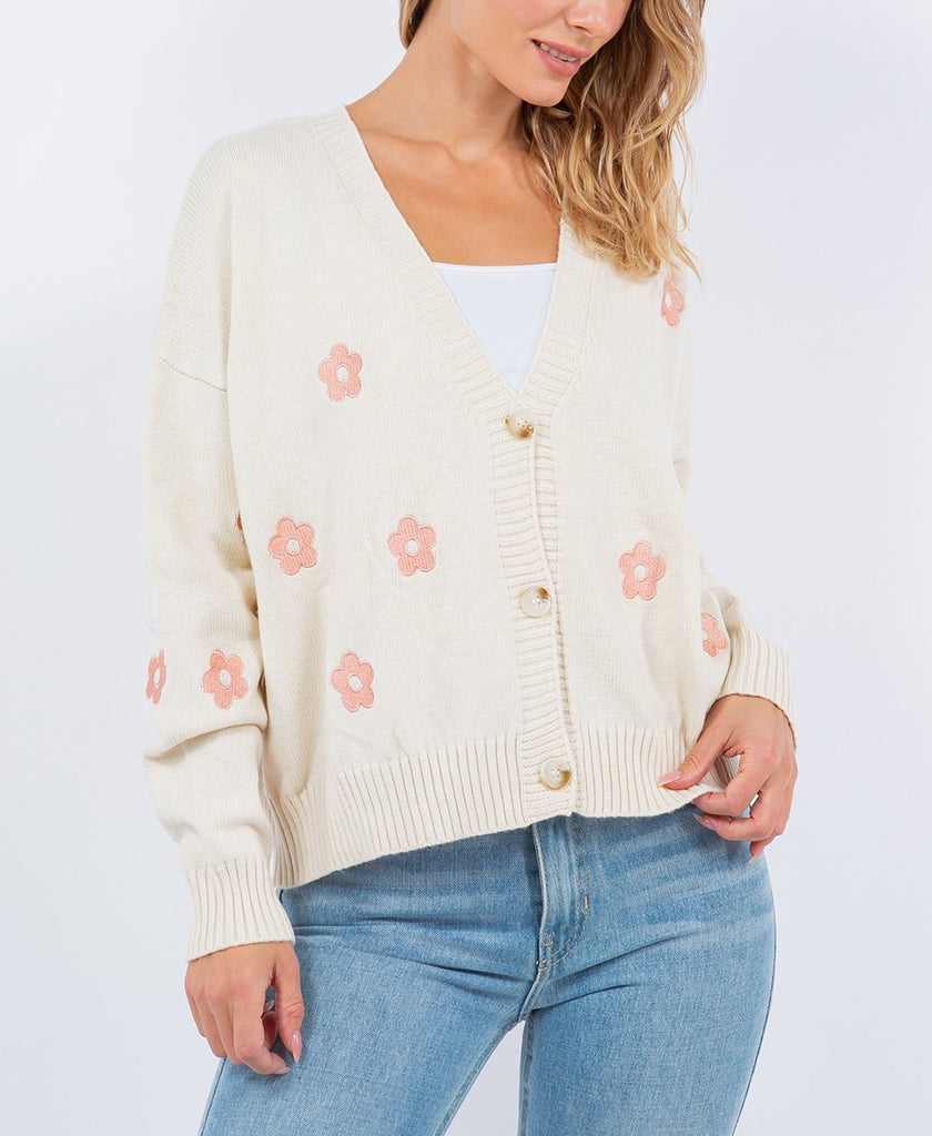 Clara Daisy Cardigan Ivory. This long sleeve cardigan features flowers throughout and button closures, the cutest item to add a touch of color and whimsy to your outfit.