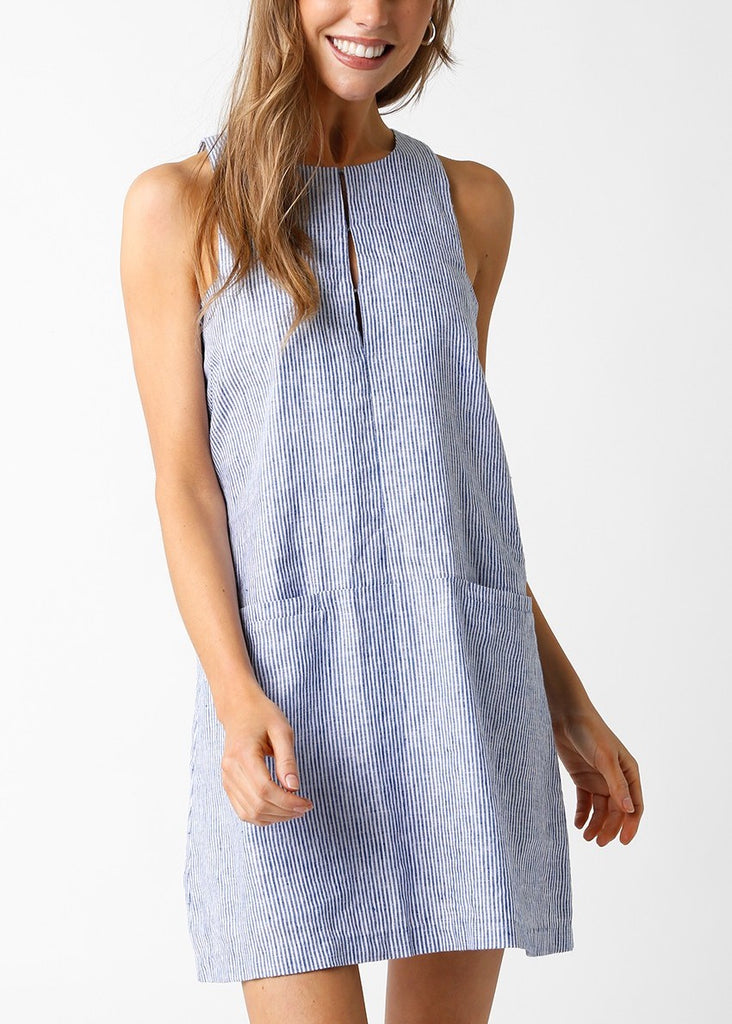 Yvette Sleeveless Linen Dress Blue Denim. This linen mini dress features a sleeveless design with a subtle stripe fabric and front pockets for a cute and casual everyday look perfect for spring or summer.