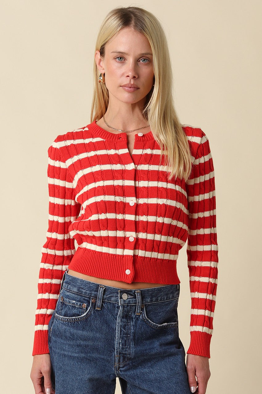 Woman wearing a cropped striped cable-knit cardigan with a round neckline and button-front closure.