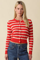 Woman wearing a cropped striped cable-knit cardigan with a round neckline and button-front closure.