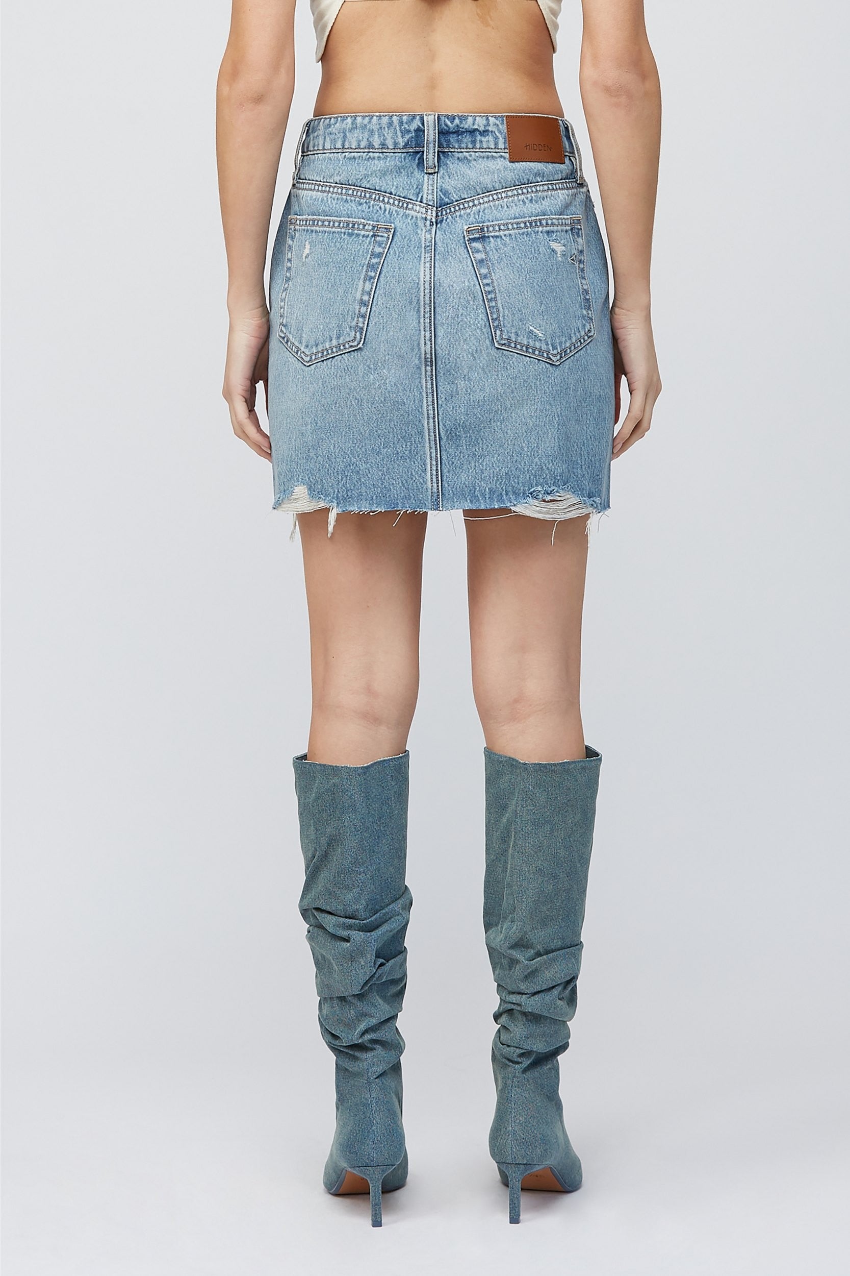 Hidden Peyton Mini Skirt Medium Blue. This classic denim mini is a closet must have for the spring and summer, in a medium blue wash featuring distressed details for a worn in timeless look.