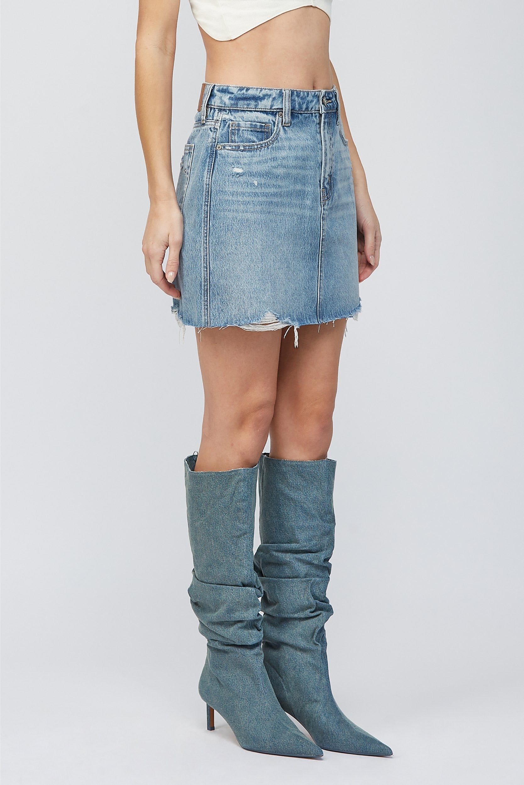 Hidden Peyton Mini Skirt Medium Blue. This classic denim mini is a closet must have for the spring and summer, in a medium blue wash featuring distressed details for a worn in timeless look.
