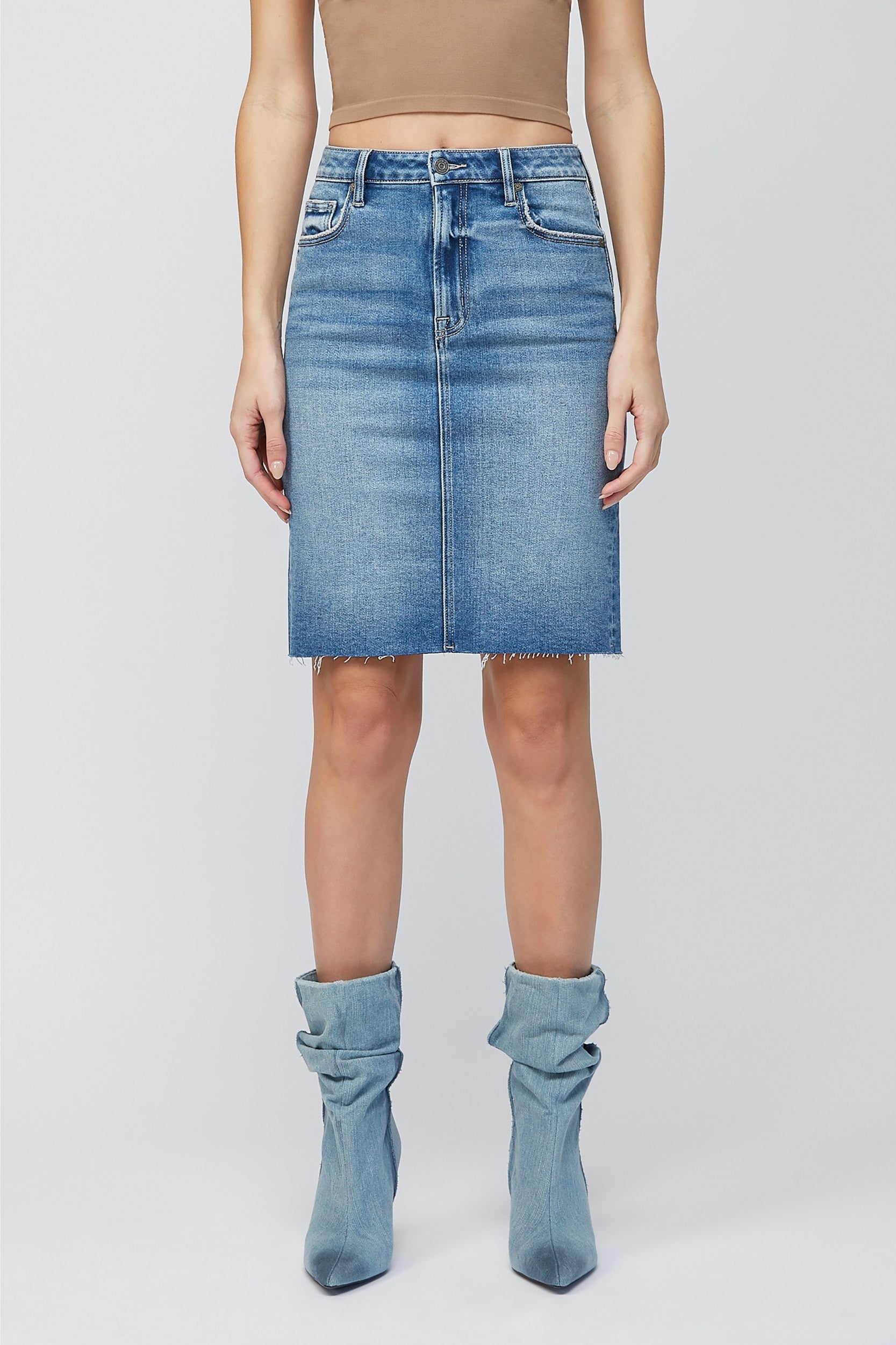 Hidden Midi Pencil Skirt Denim. This pencil skirt features a high waist with a midi length and medium blue wash with raw edge, the perfect piece to add to your spring rotation.