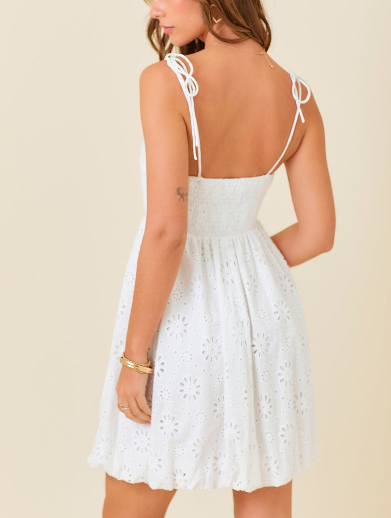Beautiful Chaos Eyelet Mini Dress White. This adorable mini dress features eyelet flowers with a tie straps and a square neckline, the perfect effortlessly cute piece to throw on for day or night.