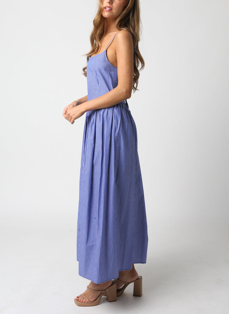 Keiran Stipe Tie Back Maxi Dress Blue Denim. This sleeveless maxi dress features a square neckline with a tie back and stripe pattern throughout, the perfect dress to throw on with heels and a white jacket.