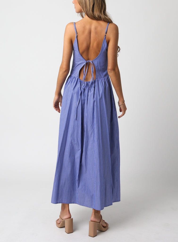 Keiran Stipe Tie Back Maxi Dress Blue Denim. This sleeveless maxi dress features a square neckline with a tie back and stripe pattern throughout, the perfect dress to throw on with heels and a white jacket.