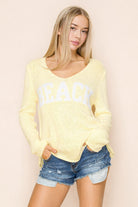 Lightweight v-neck knit sweater with relaxed fit and beach graphic styled with denim shorts