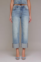 Woman wearing high rise straight leg denim jeans with oversized cuffed hem styled with heeled sandals