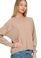 Model wearing a relaxed-fit lightweight knit sweater with drop shoulders, exposed center seam detailing, ribbed cuffs, and a ribbed hem paired with blue denim.