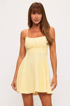 Mini dress with thin straps, gathered bust, empire waist, and flowy skirt on a model